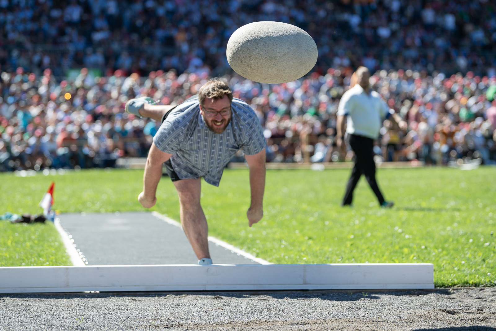 The Unspunnen Stone in flight. Daniel Kranzelbinder has released the stone and is fully extended on one leg.