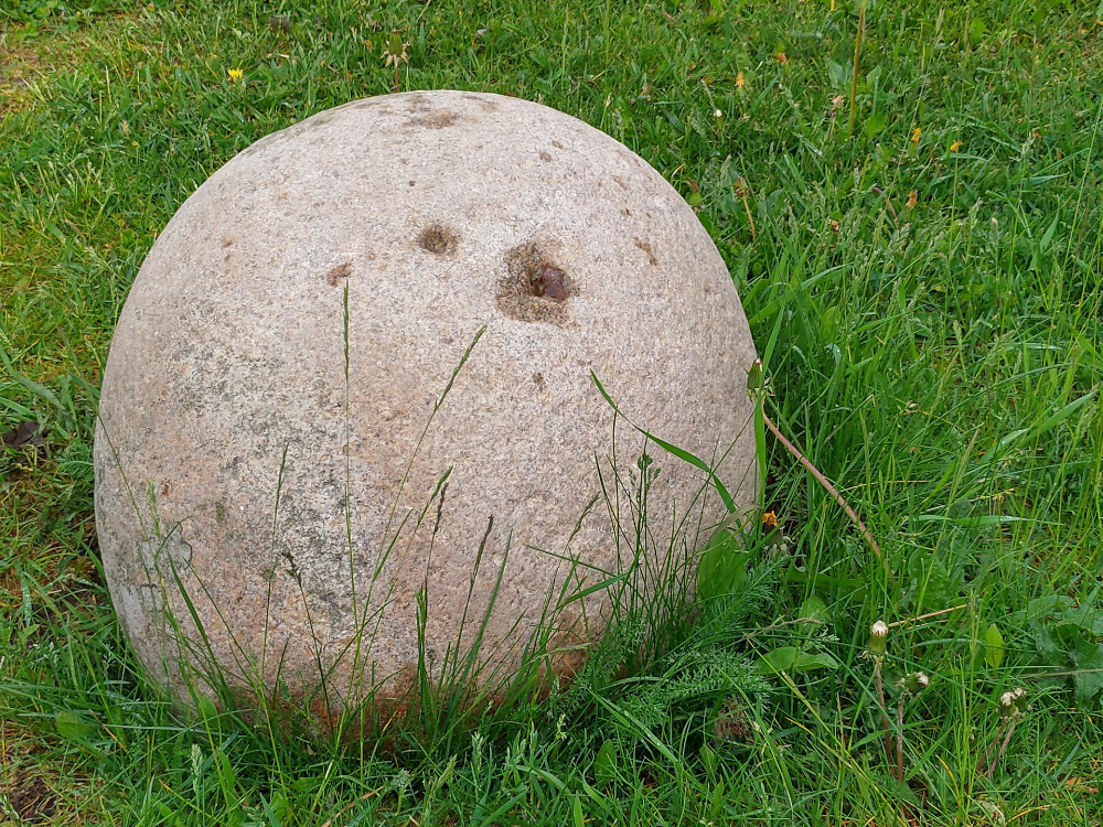 The reddish egg-shaped Karperö Lifting Stone sat in grass.
