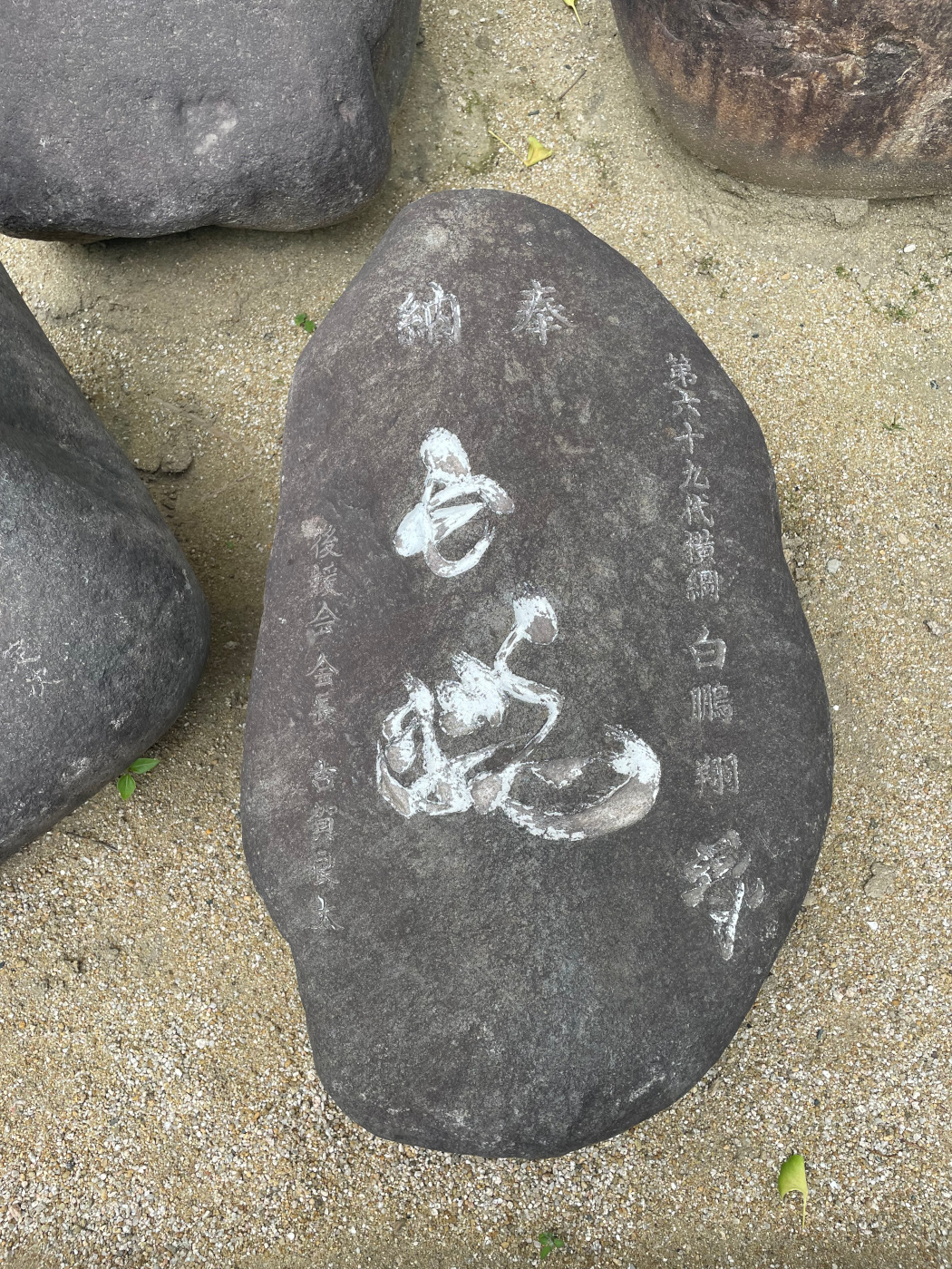 Hakuhō's power stone on display. The white paint in that filled the engravings is fading. On the bottom right-hand side of the stone is the kanji 夢, which Hakuhō engraved himself.