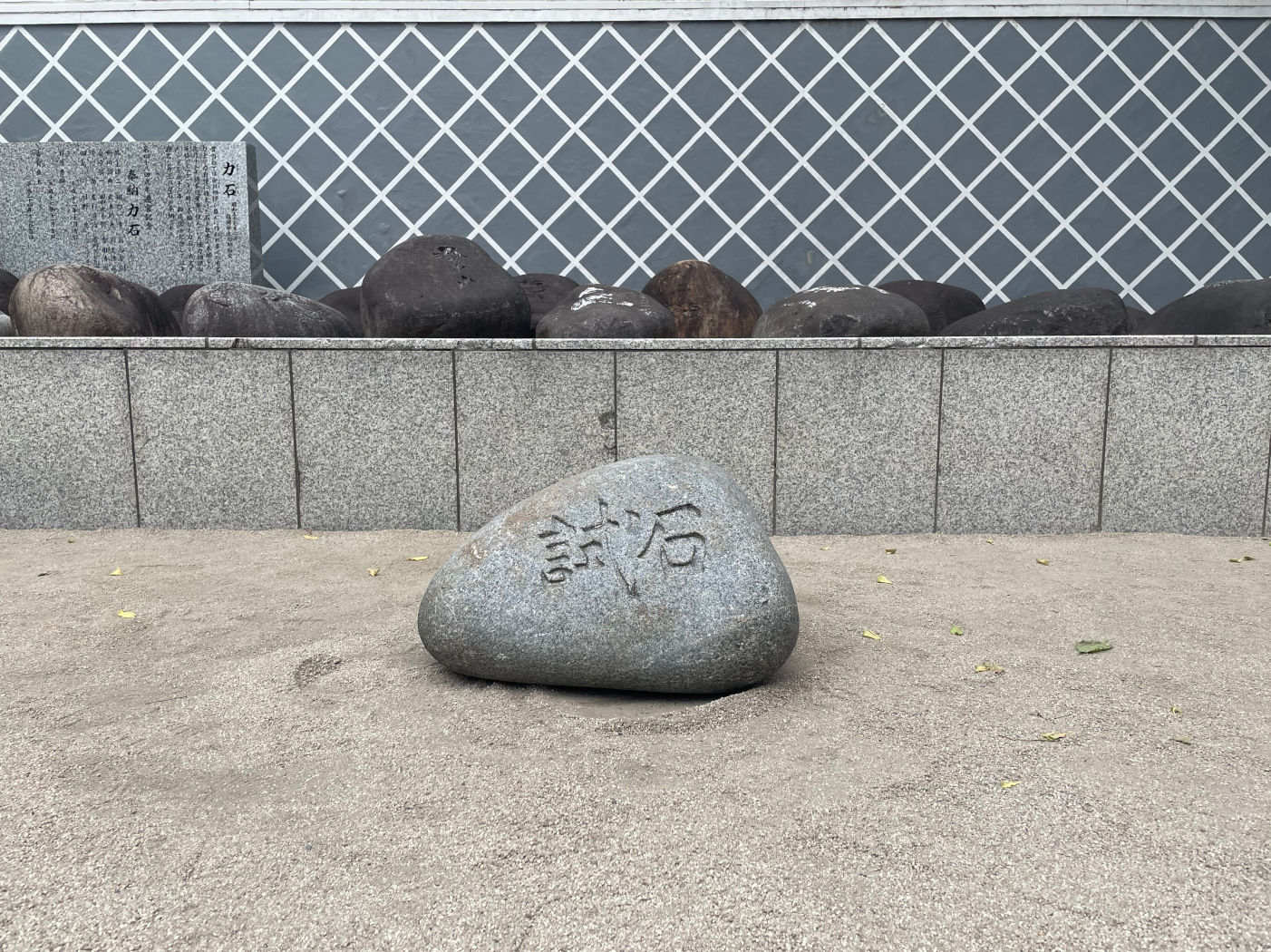 A close photo of Kushida Shrine's test stone on the gravel floor. On a platform in the background is the display of power stones.