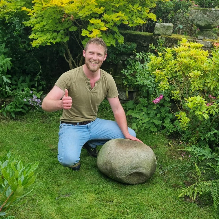 Calum Stott poses next to the Lonton Egg on the lawn. He's smiling and giving a thumbs-up.