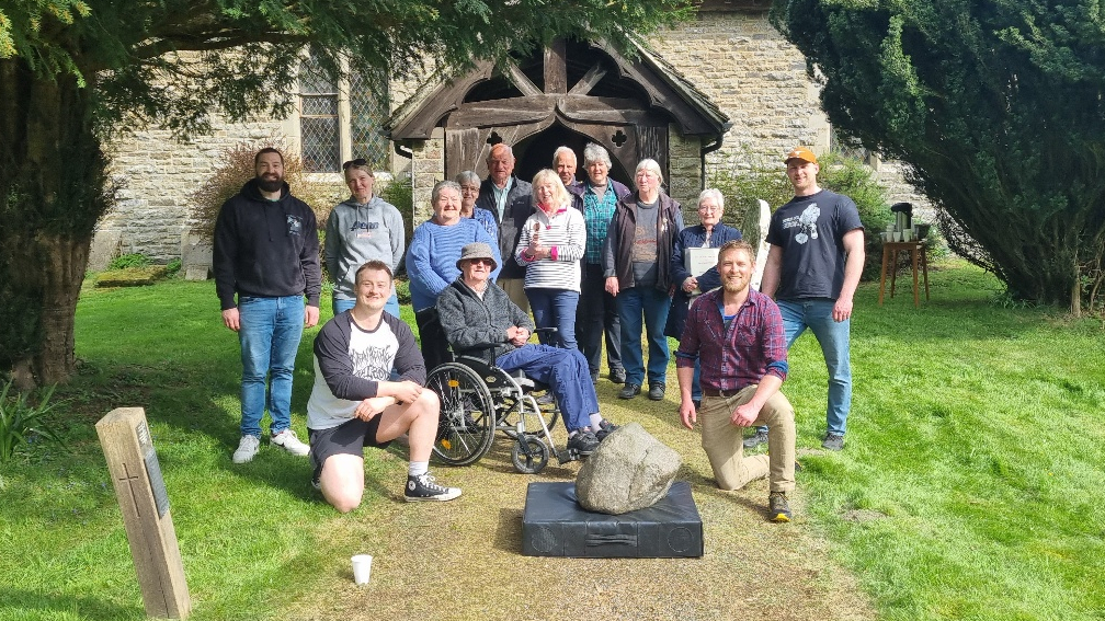A group photo with a group of 10 locals outside the church with the stone on a pad.