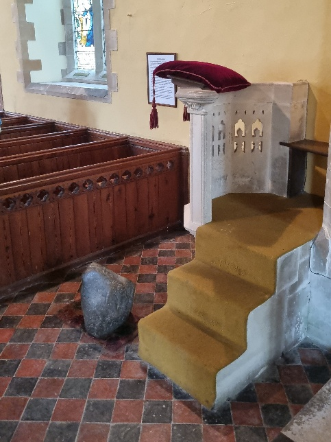 The Maegen Stone sits on the floor on top of some carpet next to the pulpit