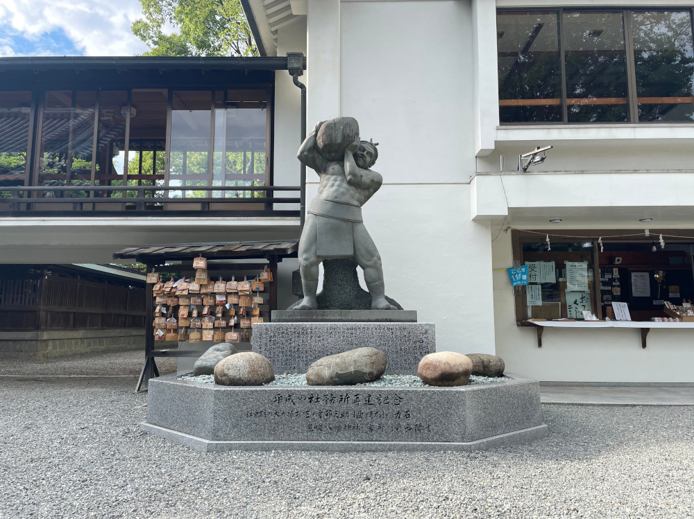 A statue of Japanese strongman Sannomiya Unosuke at the Usuki Hachiman Shine. 5 lifting stones surround the base of the statue.