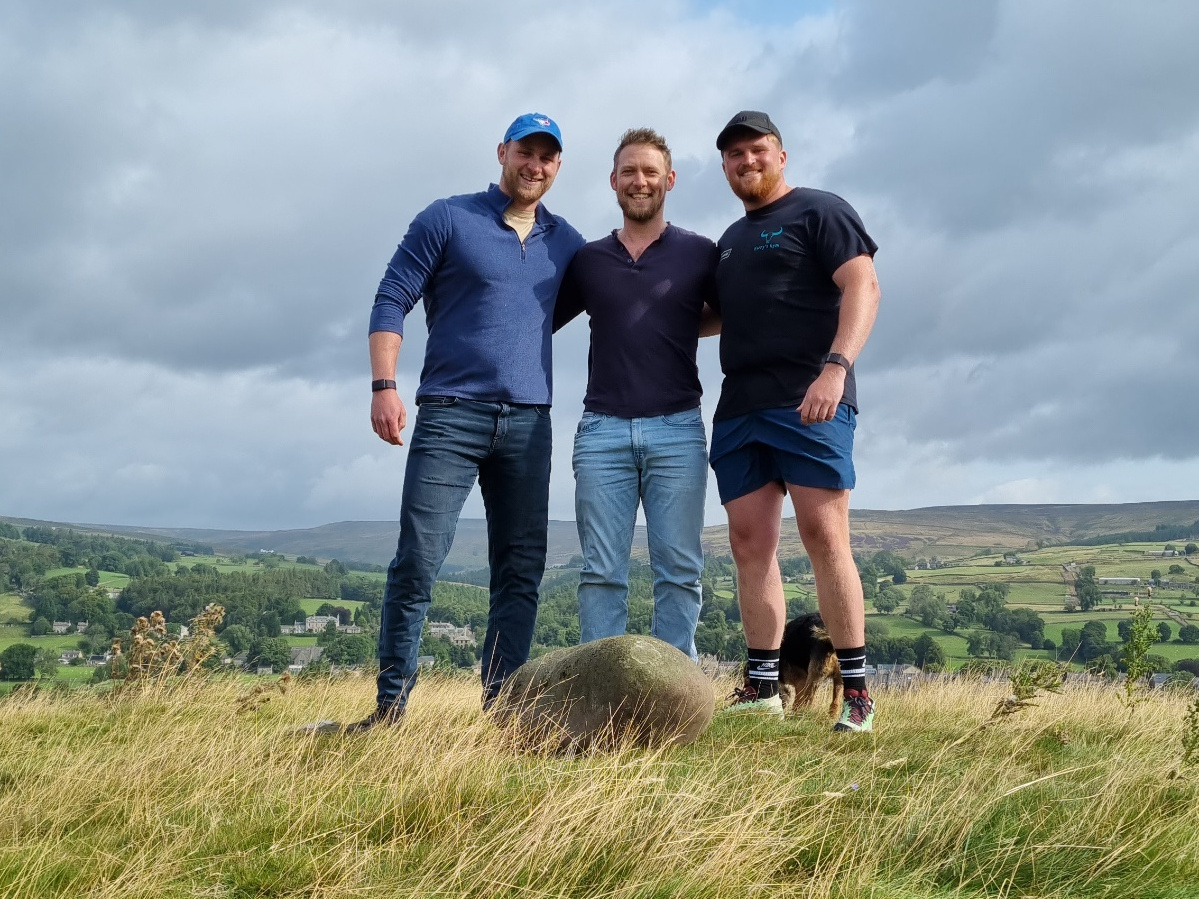 Jono, Calum, and Harry pose for a group photo on the knoll with the Teesdal Feat Stone at their feet.