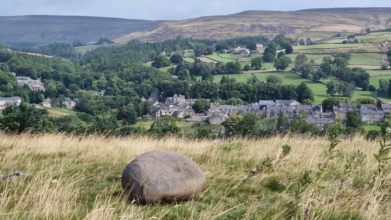 A landscape photograph from the top of the knoll looking down at Middleton. The Teesdale Feat Stone sits in the foreground.