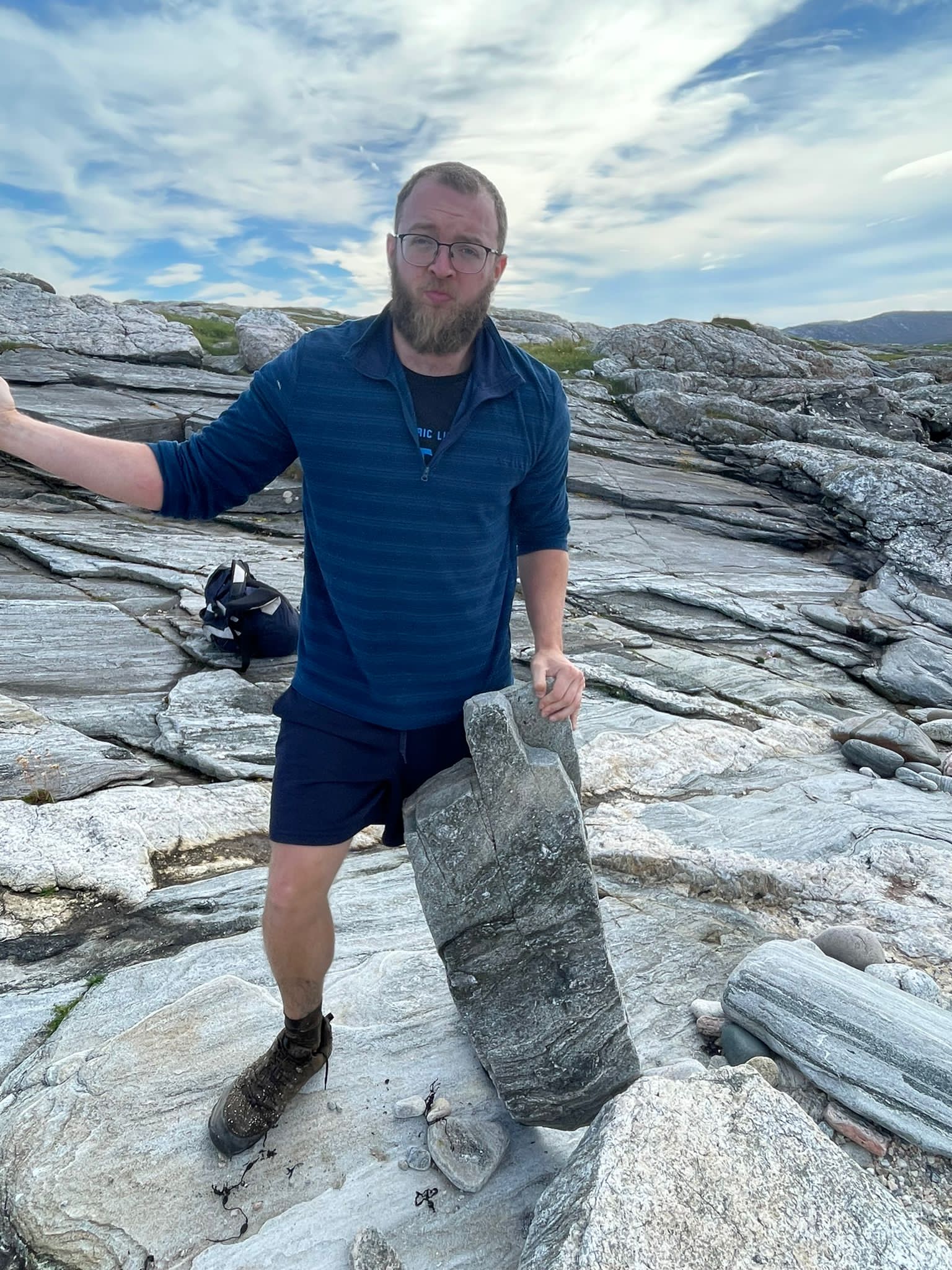 Jacob stands holding a large broken stone upright, balanced on the ground.