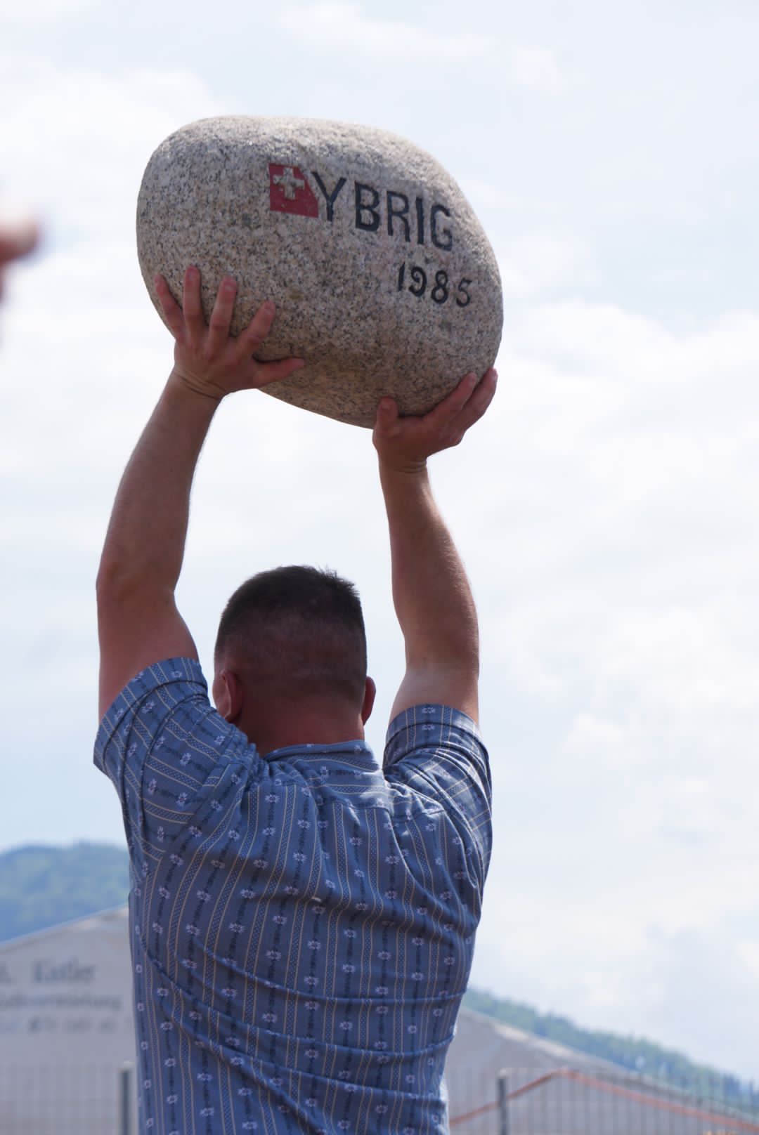 Andreas Züger holds the Ybrig Stone above his head at the Centennial Alpine Games of Schwyz in 2024.